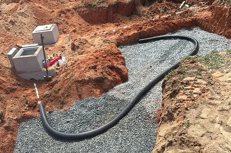 Two concrete boxes at the edge of a gravel bed with a black flexible line curving away Two concrete boxes at the edge of a gravel bed with a black flexible line curving away