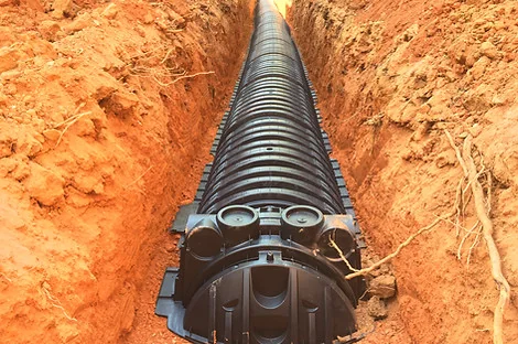 Looking down a trench of black plastic chambers with an inspection port at the start Looking down a trench of black plastic chambers with an inspection port at the start