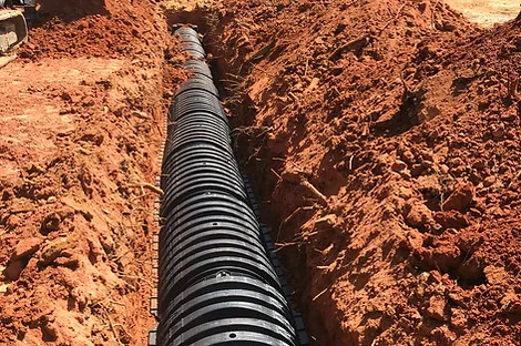 Long run of black plastic chambers laid in a straight red clay trench Long run of black plastic chambers laid in a straight red clay trench