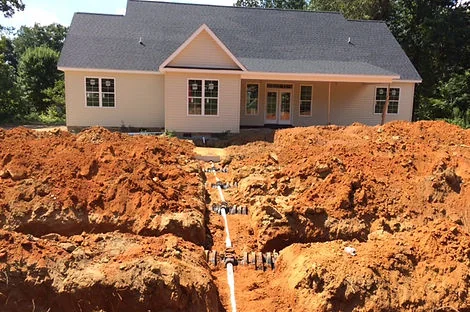 Open septic trenches with white PVC lines behind a newly built house Open septic trenches with white PVC lines behind a newly built house