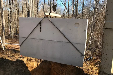 Precast septic tank lifted on chains over an excavation in a wooded lot Precast septic tank lifted on chains over an excavation in a wooded lot